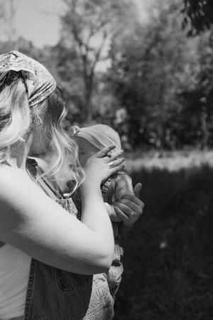 black and white photograph of a woman holding a baby in her arms with trees in the background