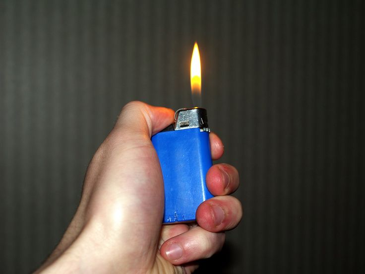 a person holding a lighter in their hand with the light on it's side