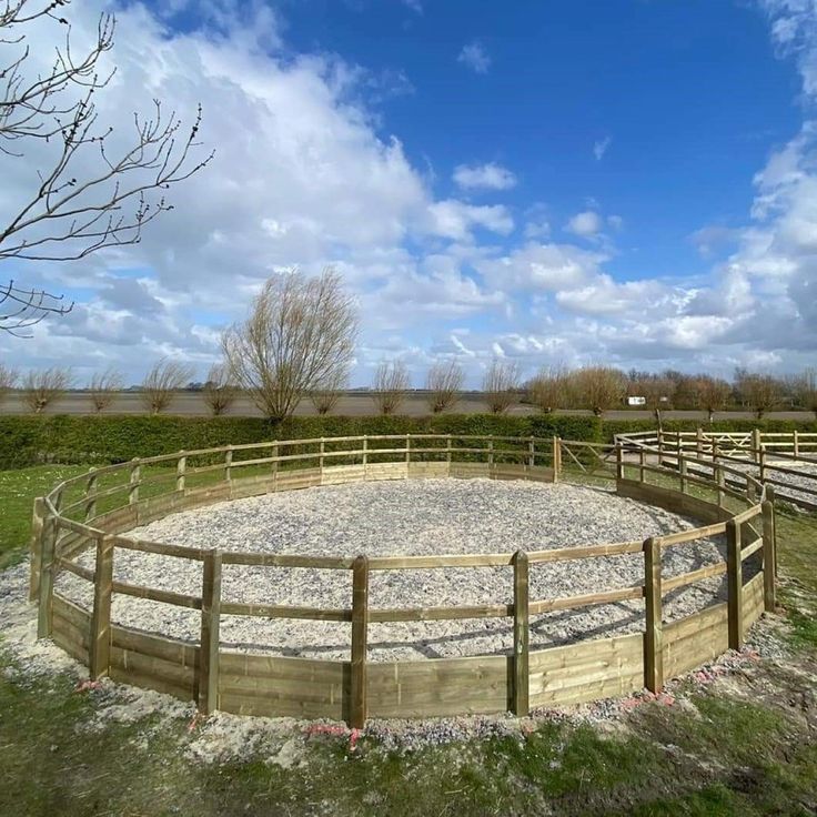 a fenced in area with gravel and grass on the ground, surrounded by wooden fences