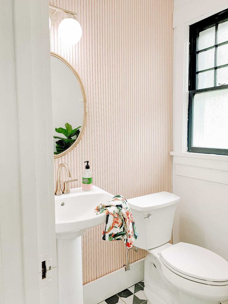 a white toilet sitting next to a sink in a bathroom under a mirror and a black and white checkered floor