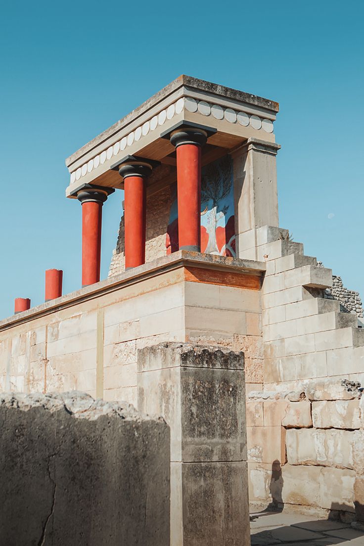 an old building with red pillars and columns on the outside, against a blue sky