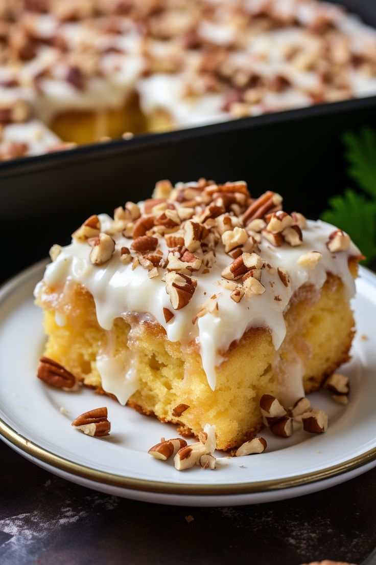 a piece of cake with white frosting and nuts on top sitting on a plate