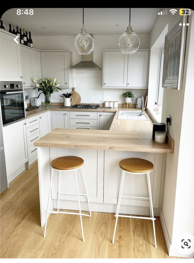 a kitchen with two stools in front of an island