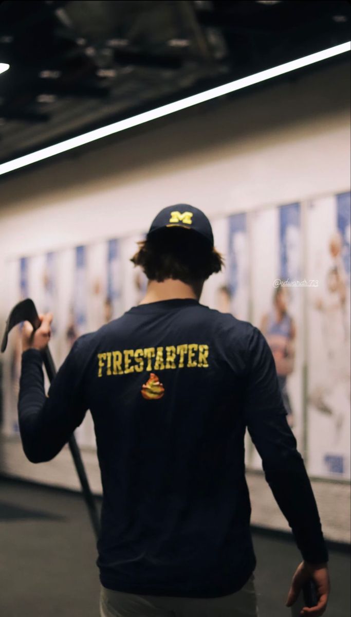 a man with a hammer in his hand walking down a hallway next to a wall