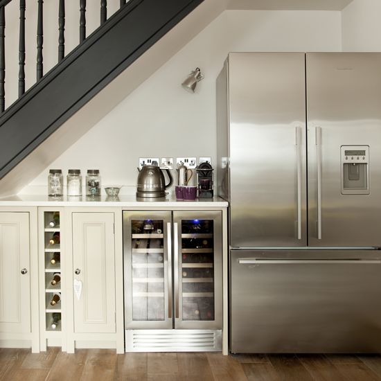 a stainless steel refrigerator and freezer combo in a kitchen with stairs leading up to the upper floor