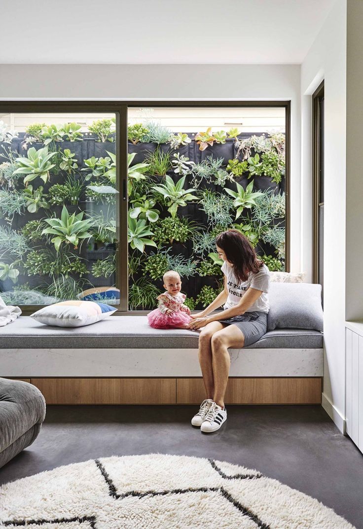 a woman sitting on top of a window sill next to a baby in a bed