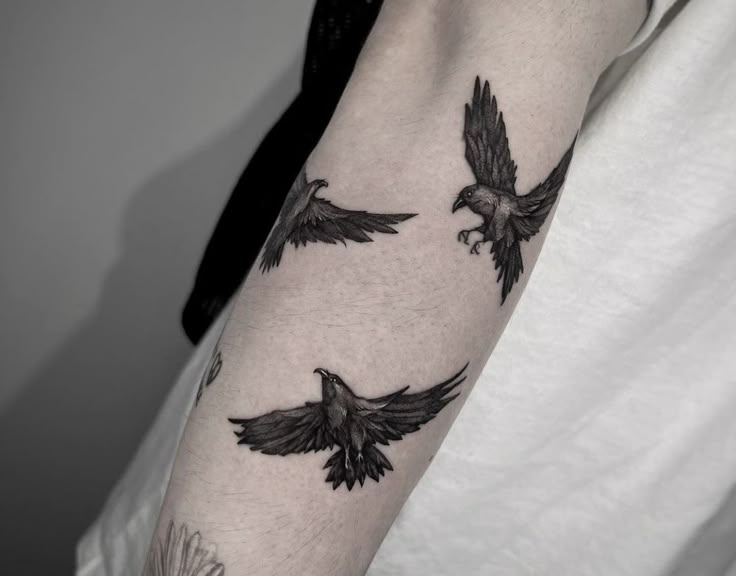 a person with a tattoo on their arm and two birds flying in the sky above them