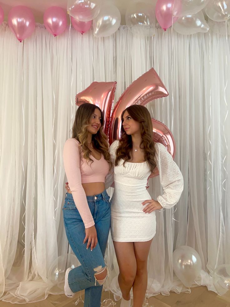 two women standing next to each other in front of balloons