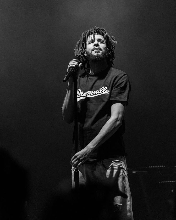 a man with dreadlocks on his head standing in front of a microphone at a concert