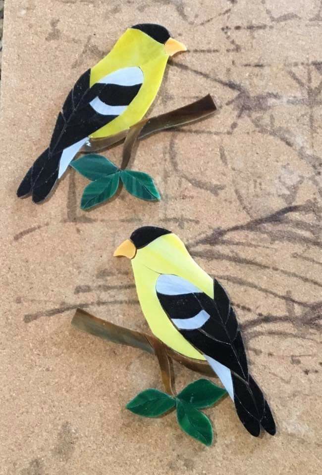 two paper birds sitting on top of a wooden branch next to another bird with green leaves