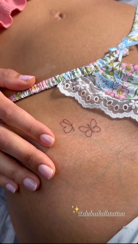 a close up of a person's stomach with tattoos on her belly and bra