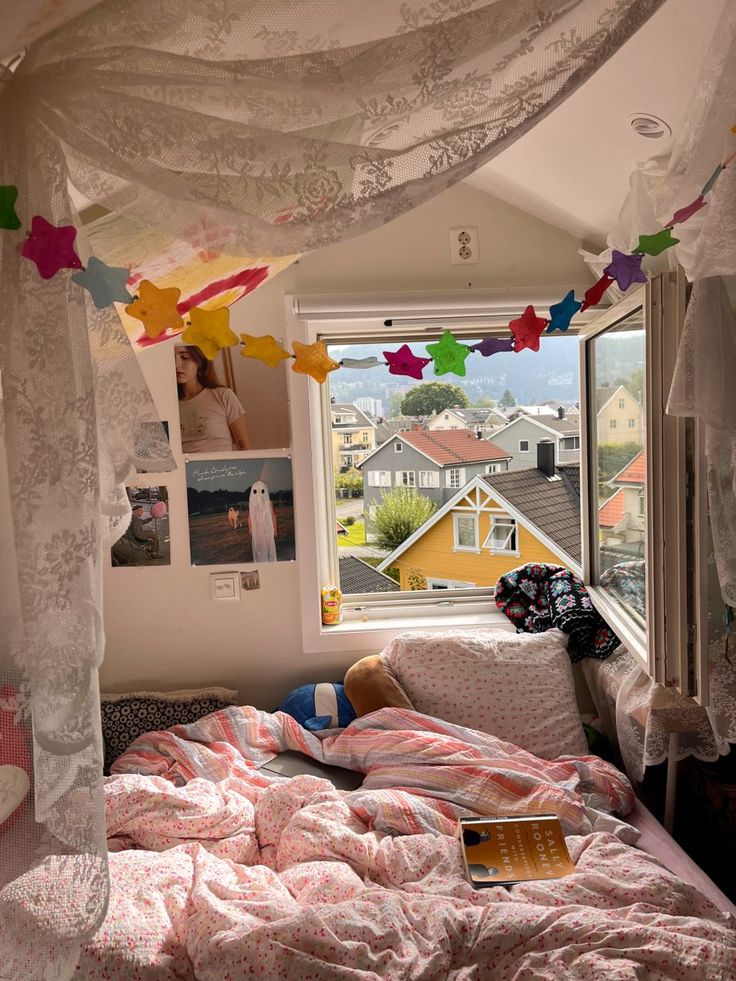 a bedroom with pink bedding and lots of pictures hanging from the ceiling above it