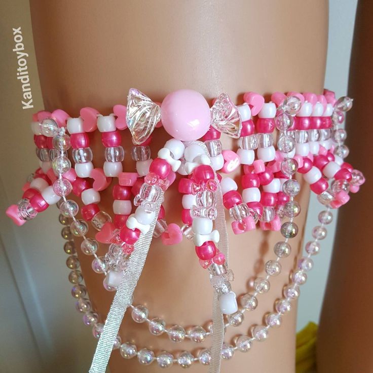 a pink and white bracelet with beads on it's side, attached to a mannequin