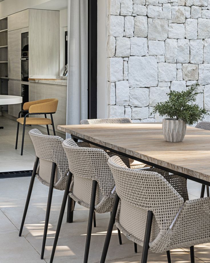 a table with chairs and a potted plant sitting on it's side in front of a stone wall