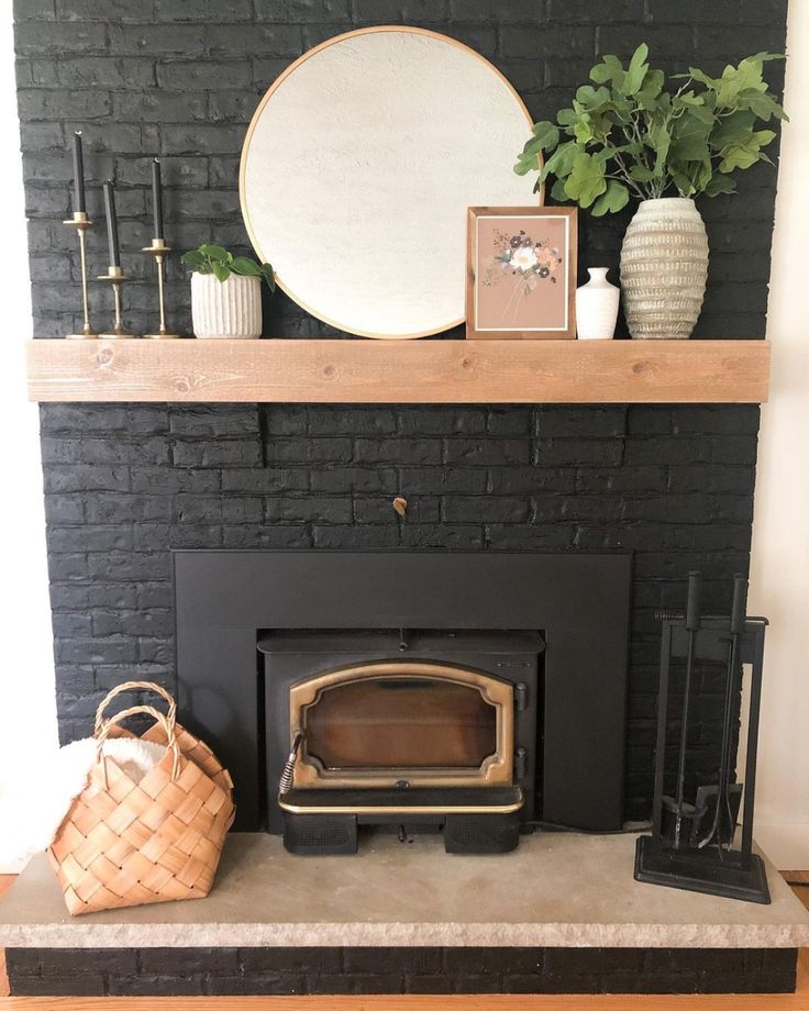 a black fireplace with a wood burning stove in the middle and some plants on top