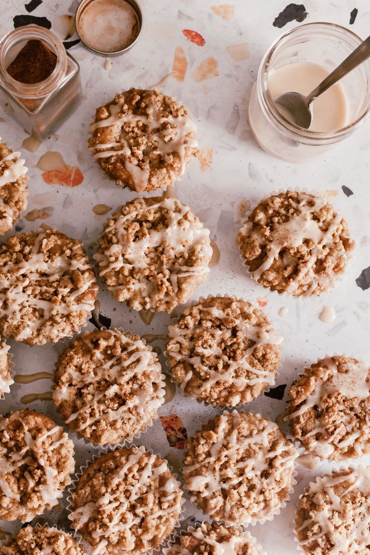 several cookies with white frosting on a table next to some jars and spoons