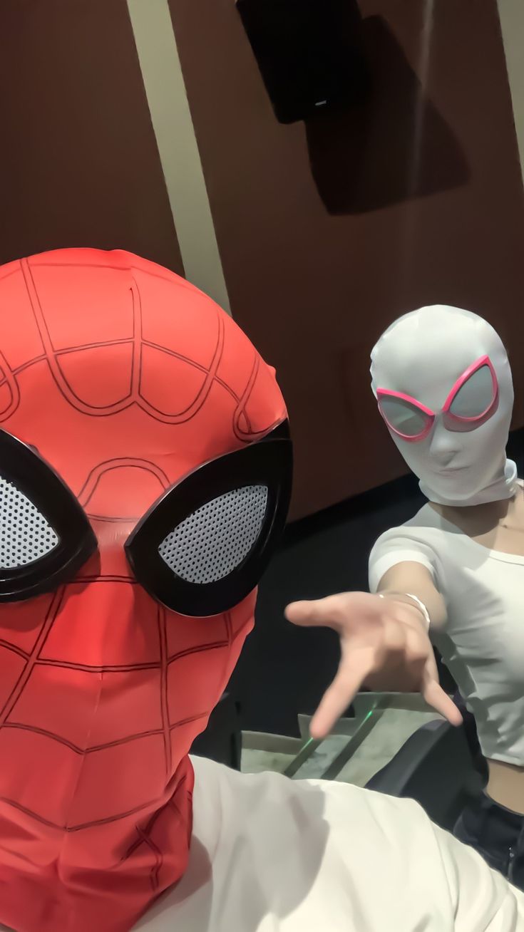 a person wearing a spider man mask and pointing to the side with their hands in front of them