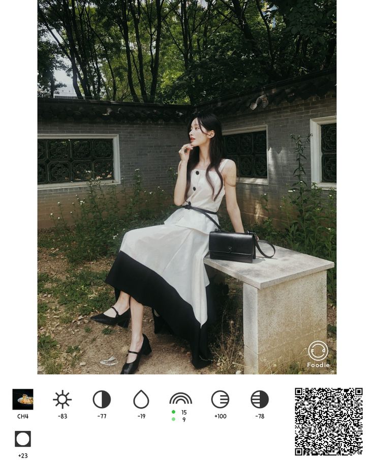 a woman sitting on top of a cement bench next to a wall and trees in the background