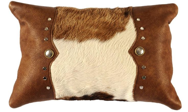 a brown and white cowhide pillow with studded details on the front, sitting against a white background