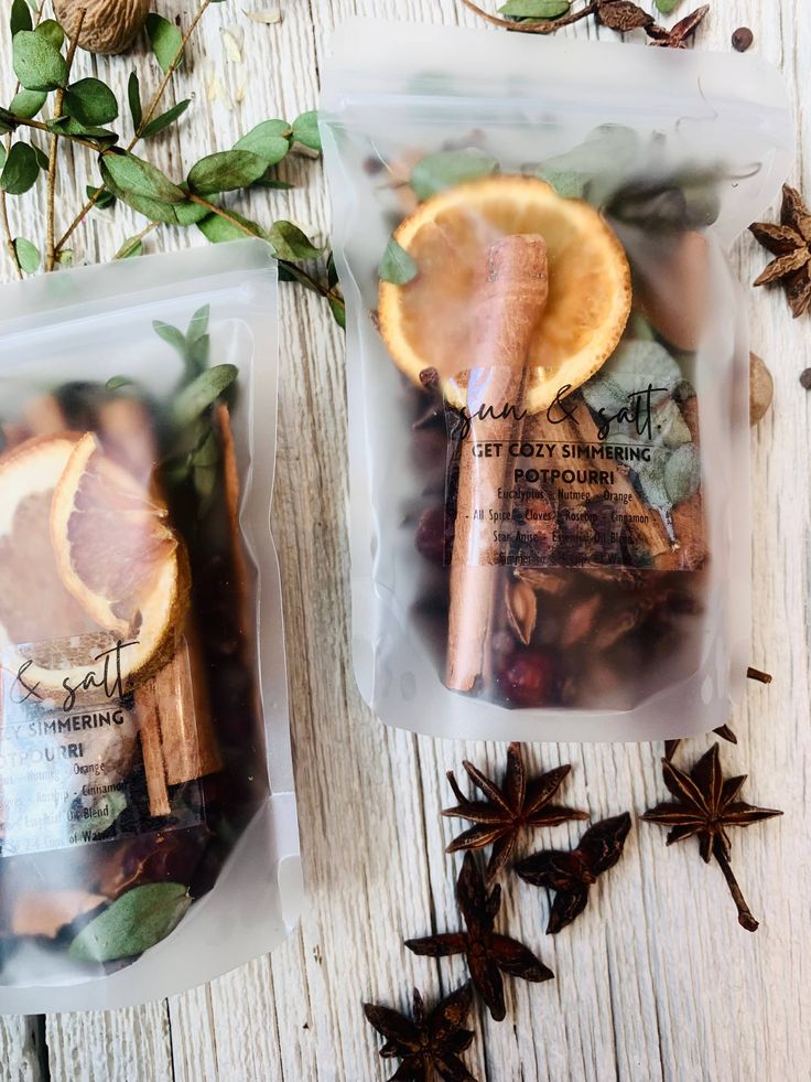 two bags filled with orange slices and cinnamons on top of a wooden table next to star anise