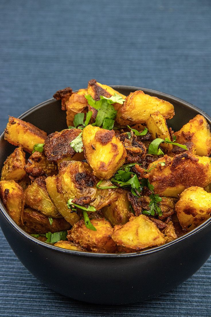 a black bowl filled with fried potatoes on top of a blue table