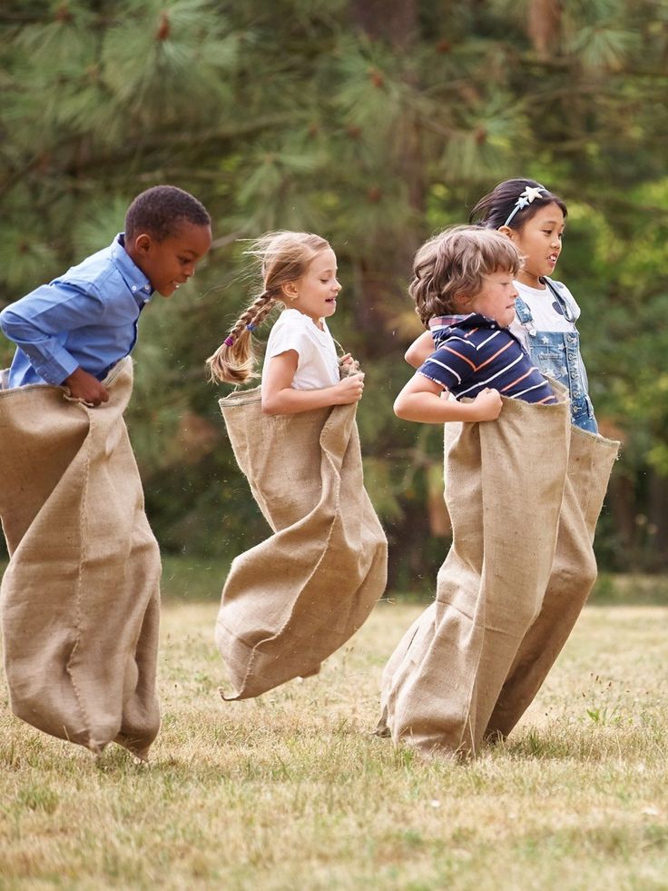 four children are playing in the grass with their pants on and one child is wearing a blue shirt