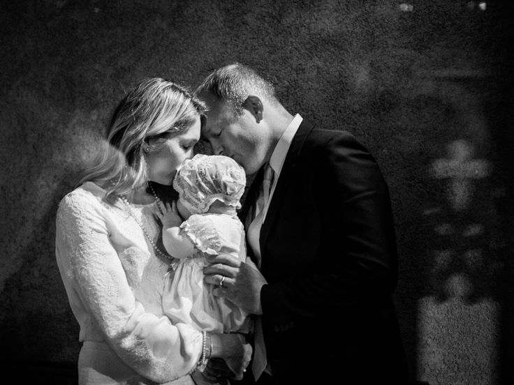 black and white photograph of a man and woman holding a baby in front of a wall