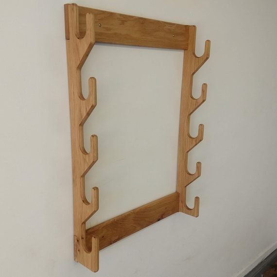 a wooden frame hanging on the wall with hooks attached to it's sides,