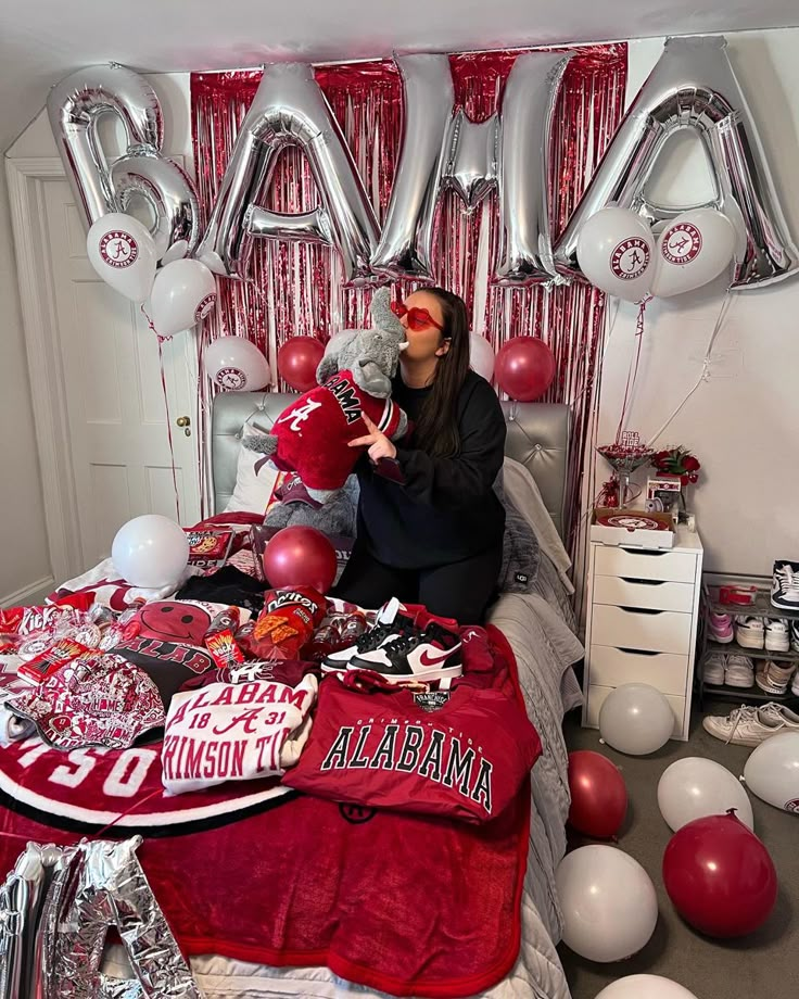 a woman sitting on top of a bed in front of balloons and letters that spell out the word love