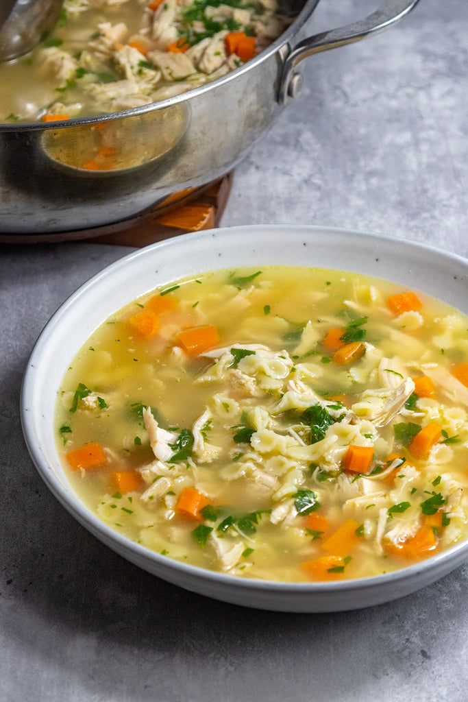 two bowls of chicken noodle soup on a table