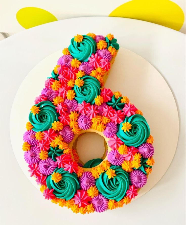 a colorful cake with the number six made out of cupcakes and icing