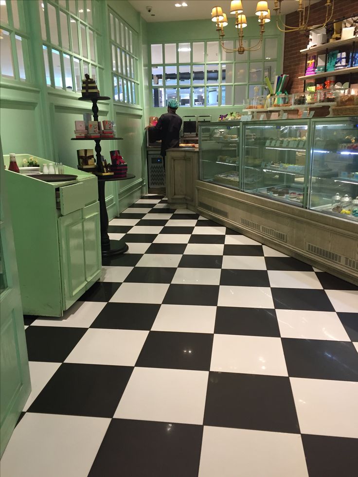 a black and white checkered floor in a bakery with green cabinets, counter tops and shelves