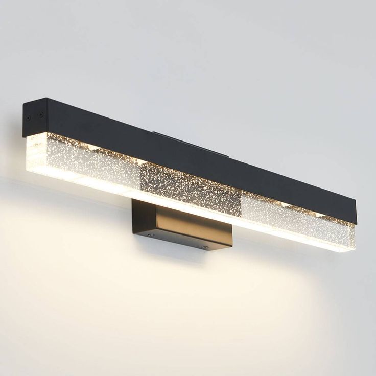 a wall mounted light that is on the side of a wall with white and gold glitters