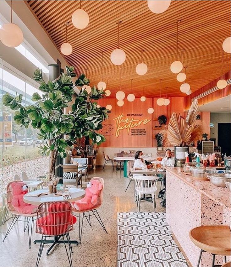 the inside of a restaurant with tables, chairs and potted plants on the counter