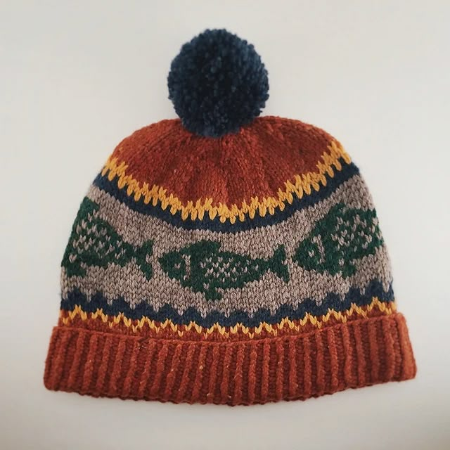 a knitted hat with a pom - pom on the top is shown