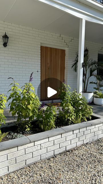 a white brick house with plants in the front yard