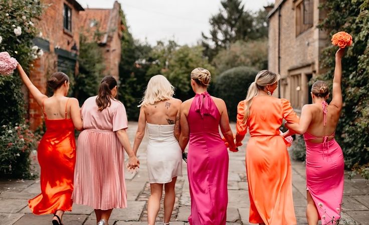 four bridesmaids in different colored dresses walking down the street