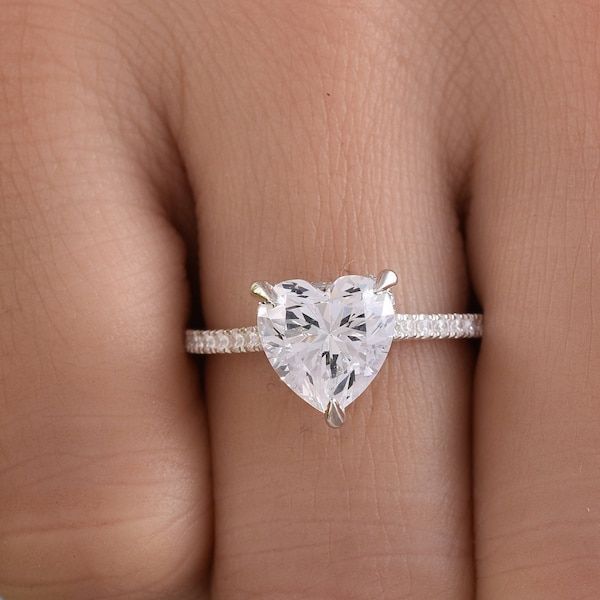 a woman's hand holding a heart shaped diamond ring