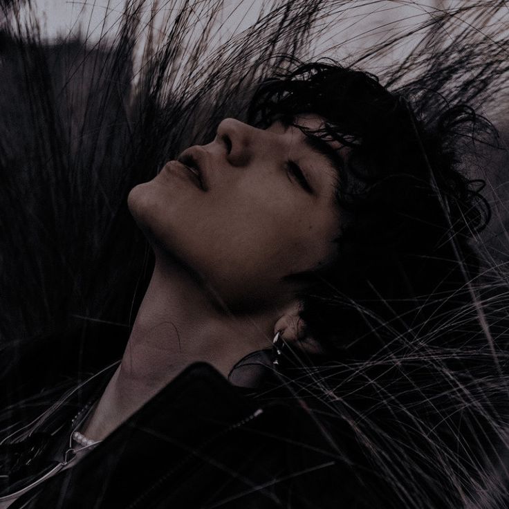 a woman with her eyes closed laying on the ground next to some tall dry grass