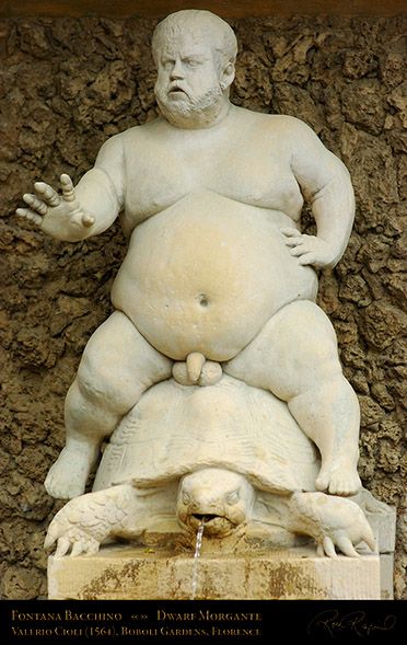 a statue of a man sitting on top of a turtle next to a stone wall