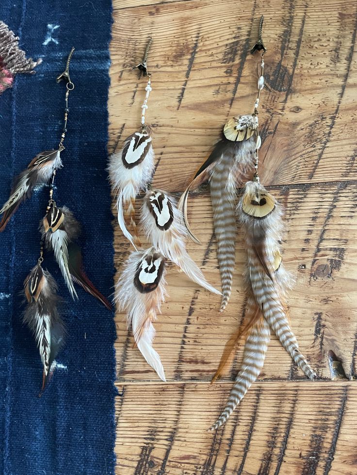 several feathers are hanging from chains on a wooden table next to another piece of cloth