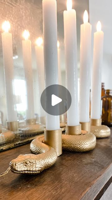 candles are sitting on top of a wooden table with gold snake figurines next to them