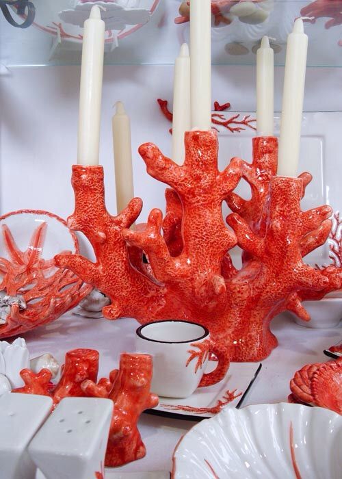 an orange coral candle holder is surrounded by other red corals and white china dishes