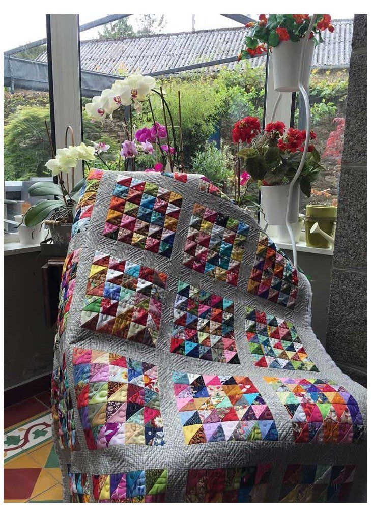 a quilted chair sitting in front of a window with potted flowers on it