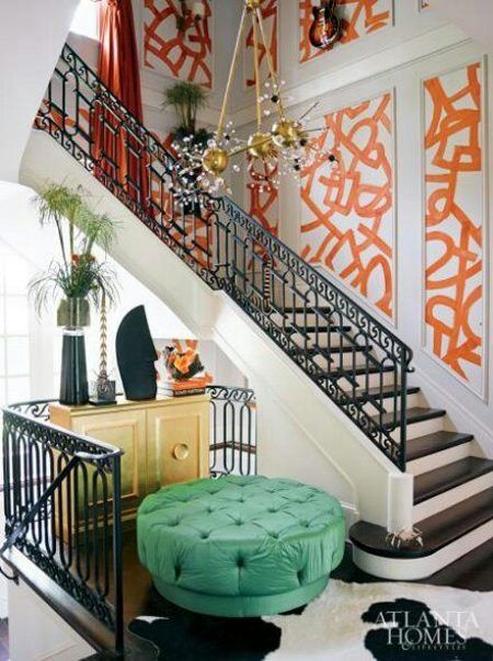 the stairs in this home are decorated with orange and black accents, along with a green ottoman