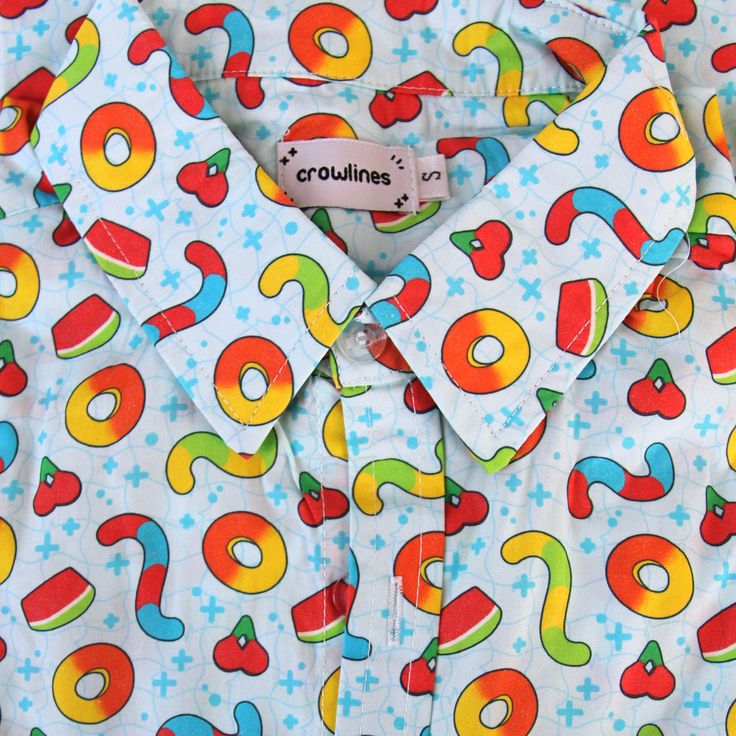 Light blue button up shirt patterned with various gummy candies including red and blue gummy worms, yellow and green gummy worms, peach rings, cherries, and watermelon slices. Between the candies are blue sparkles and a faint wavy grid background. Sour Gummy Candy, Silly Clothes, Candy Buttons, Funky Outfits, How To Measure, Gummy Candy, Character Outfits, Christmas Tshirts, Button Up Shirt