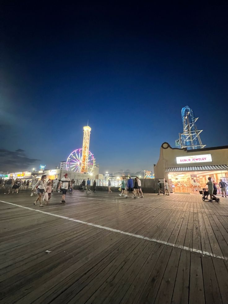 people are walking around on the boardwalk at night