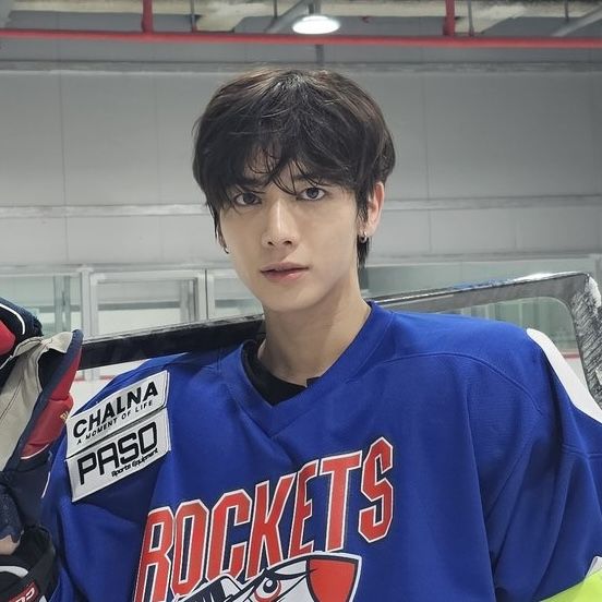 a young man wearing a hockey jersey and gloves