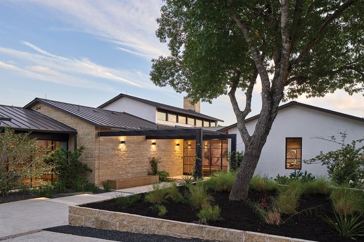 a house with a tree in front of it and landscaping on the side walk next to it