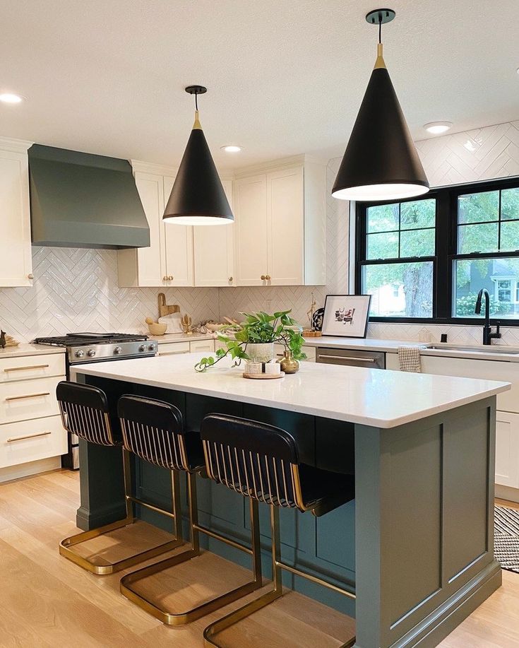 a kitchen island with three stools in front of it and two lights hanging from the ceiling